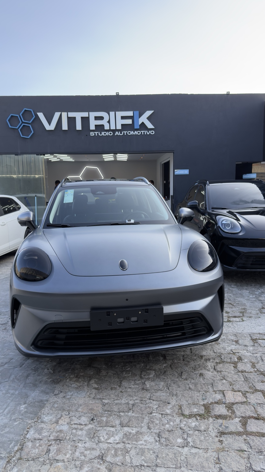 Carro cinza fosco diante da fachada da Vitrifik Studio Automotivo